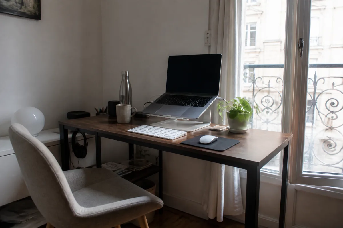 Poste de télétravail avec ordinateur portable surélevé, clavier externe, souris et écran placé face à l’utilisateur